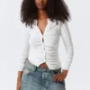 Schmal geschnittene Strickjacke mit Rüschen und Knopfleiste – Off-White Schmal geschnittene Strickjacke mit Rüschen und Knopfleiste – Off-White
